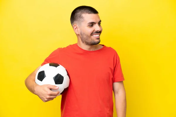 Young Caucasian Man Playing Soccer Isolated Yellow Background Looking Side — Foto Stock