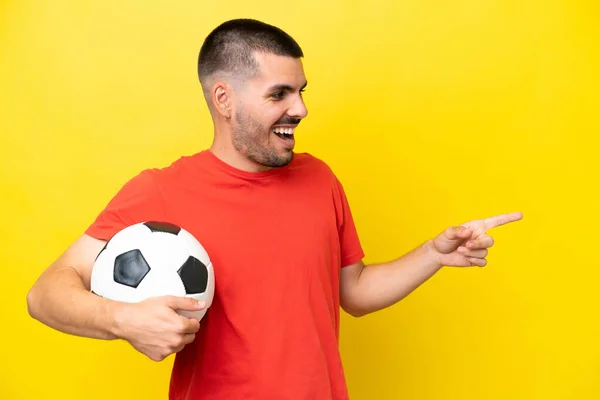 Giovane Uomo Caucasico Giocare Calcio Isolato Sfondo Giallo Puntando Dito — Foto Stock