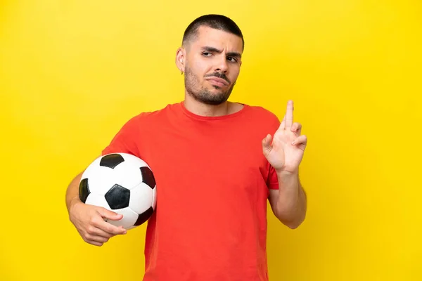 Young Caucasian Man Playing Soccer Isolated Yellow Background Fingers Crossing — Stock Photo, Image