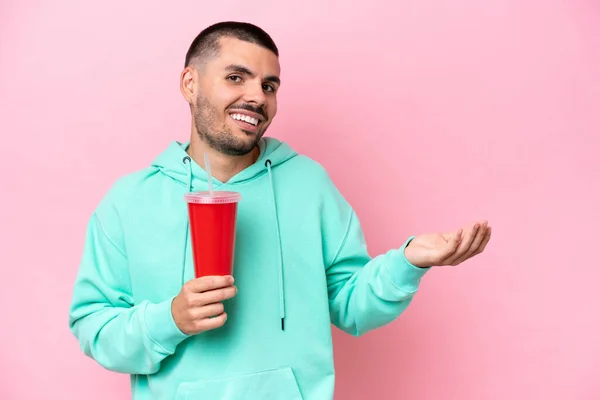 Young Caucasian Man Holding Soda Isolated Pink Background Extending Hands — 스톡 사진