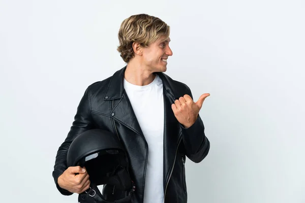 English man holding a motorcycle helmet pointing to the side to present a product