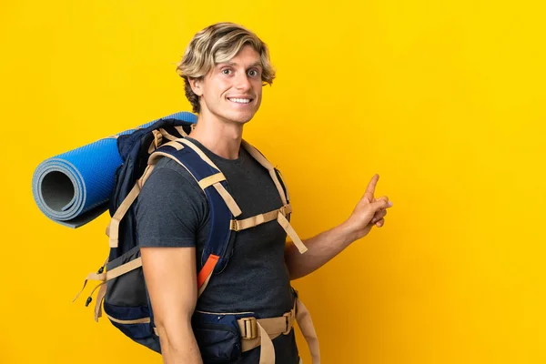 Young Mountaineer Man Isolated Yellow Background Pointing Back — Zdjęcie stockowe