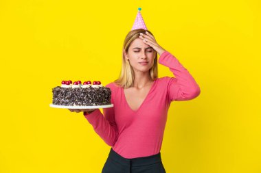 Sarışın Uruguaylı kız elinde doğum günü pastası ile sarı arka planda baş ağrısı ile izole edilmiş.