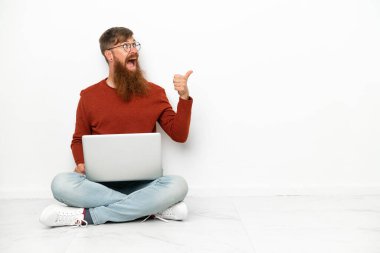 Beyaz arka planda dizüstü bilgisayarı olan genç, beyaz beyaz bir adam çözümü bulmak için parmağını kaldırıyor.