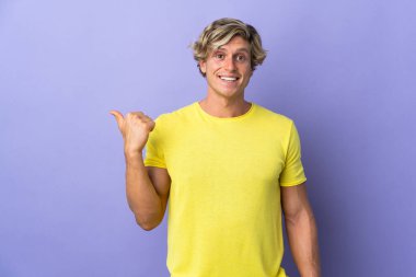 Soyutlanmış mor arka planda İngiliz bir adam bir ürün sunmak için kenarı işaret ediyor