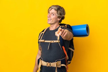 Genç dağcı, izole edilmiş sarı arka planda mutlu bir ifadeyle öne bakıyor.