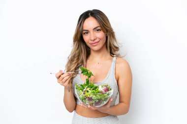 Beyaz arka planda izole edilmiş beyaz bir kadın elinde mutlu bir ifadeyle bir kase salata tutuyor.