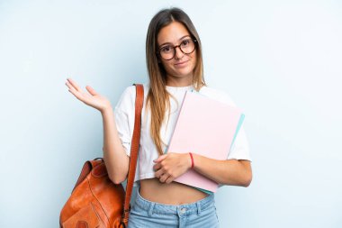 Mavi arka planda izole edilmiş genç bir kız öğrencinin ellerini kaldırırken şüpheleri vardı.