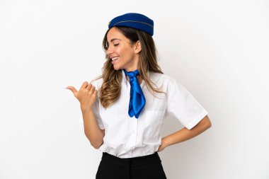 İzole edilmiş beyaz arka planda uçak hostesi bir ürünü sunmak için kenarı işaret ediyor.