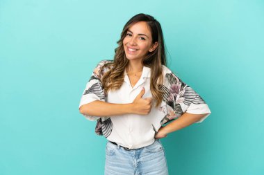 Soyutlanmış mavi arka planda genç bir kadın baş parmak işareti yapıyor.