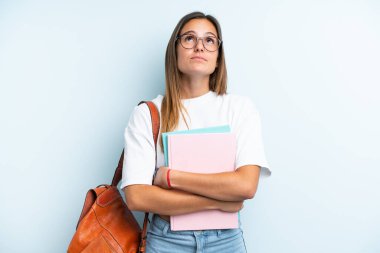 Genç bir bayan öğrenci mavi arka planda izole edilmiş ve araştırılıyor.