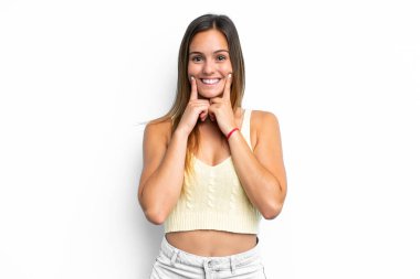 Beyaz arka planda izole edilmiş genç beyaz kadın mutlu ve hoş bir ifadeyle gülümsüyor.