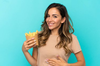 İzole edilmiş arka planda kızarmış cips tutan genç bir kadın.