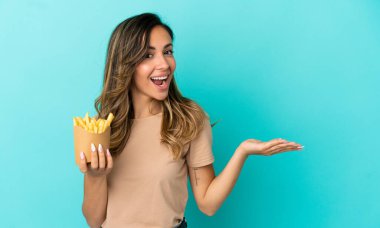 Kızarmış cipsleri izole edilmiş arka planda tutan genç bir kadın. Davet edilmek için ellerini yana uzatıyor.