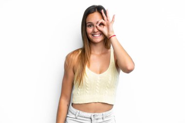 Beyaz arka planda izole edilmiş genç beyaz kadın parmaklarıyla tamam işareti gösteriyor.