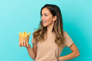 Kızarmış cipsleri izole edilmiş arka planda tutan genç bir kadın yana bakıyor ve gülümsüyor.
