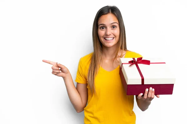 Young Caucasian Woman Holding Gift Isolated White Background Surprised Pointing —  Fotos de Stock