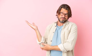 Pembe arka planda izole edilmiş yaşlı Hollandalı adamın şüpheleri var.