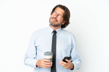 Hollandalı kıdemli iş adamı beyaz arka planda izole edilmiş. Elinde kahve ve bir şeyler düşünürken cep telefonu var.