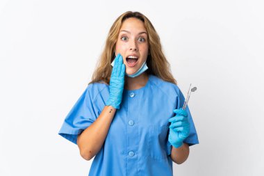 Woman dentist holding tools isolated on white background with surprise and shocked facial expression
