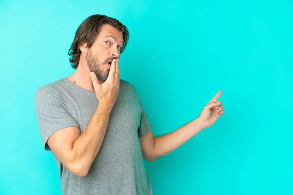 Senior Dutch Man Isolated Blue Background Surprise Expression While Pointing — Φωτογραφία Αρχείου