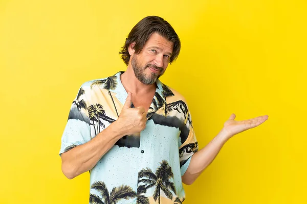 Senior Dutch Man Isolated Yellow Background Holding Copyspace Imaginary Palm — Stok fotoğraf