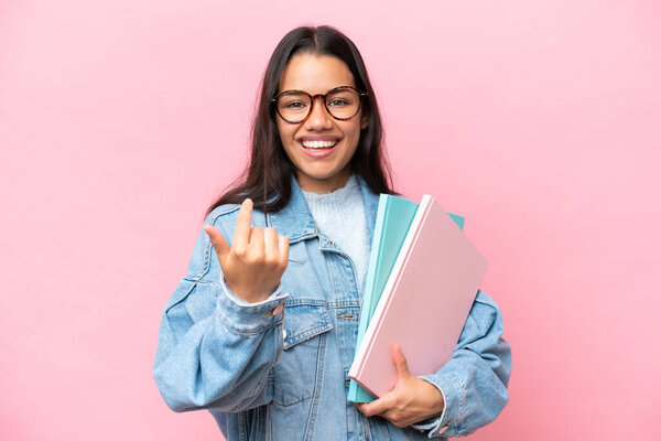 Young student Colombian woman isolated on pink background doing coming gesture