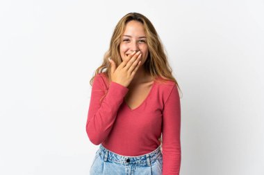 Mavi arka planda izole edilmiş genç sarışın kadın mutlu ve gülümsüyor.