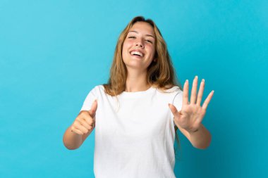 Mavi arka planda izole edilmiş genç sarışın kadın parmaklarıyla altısını sayıyor.