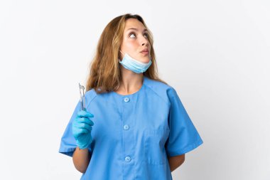 Kadın dişçi beyaz arka planda izole araçlar tutuyor ve yukarı bakıyor