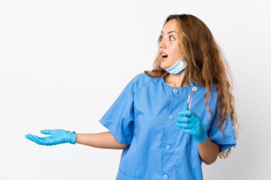 Woman dentist holding tools isolated on white background with surprise expression while looking side