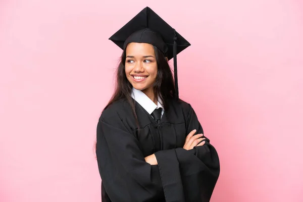 Young university Colombian woman graduate isolated on pink background with arms crossed and happy