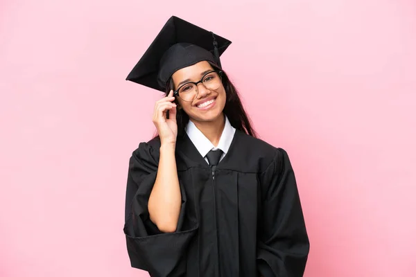 Young university Colombian woman graduate isolated on pink background with glasses and happy