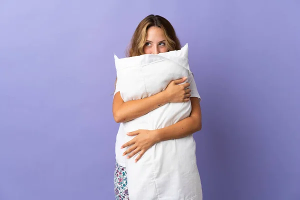 Young Blonde Woman Isolated Purple Background Pajamas Holding Pillow — Fotografie, imagine de stoc