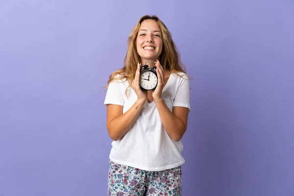 Giovane Donna Bionda Isolata Sfondo Viola Pigiama Tenendo Orologio Con — Foto Stock