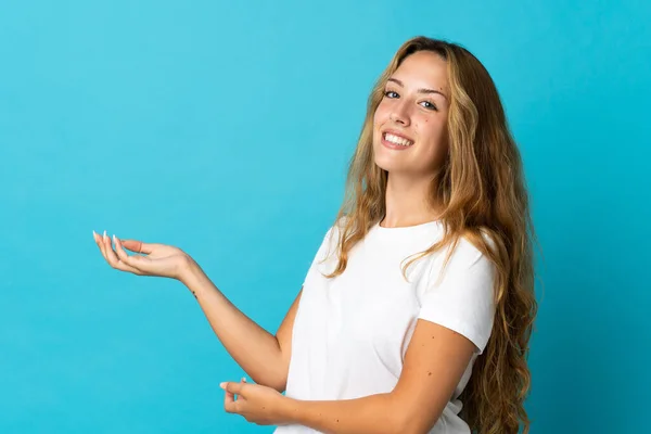 Jonge Blonde Vrouw Geïsoleerd Blauwe Achtergrond Uitstrekken Handen Naar Zijkant — Stockfoto