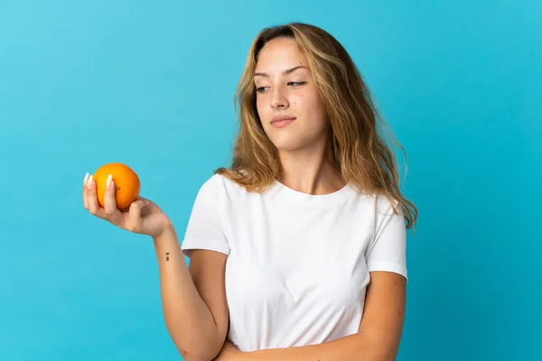 Junge Blonde Frau Isoliert Auf Blauem Hintergrund Mit Einer Orange — Stockfoto