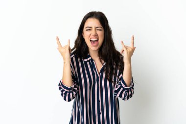 Tecrit edilmiş arka planda genç beyaz bir kadın boynuz hareketi yapıyor.