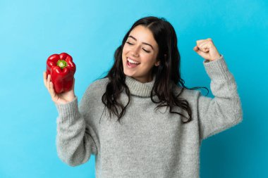 Mavi arka planda biber tutan beyaz bir kadın zaferi kutluyor.