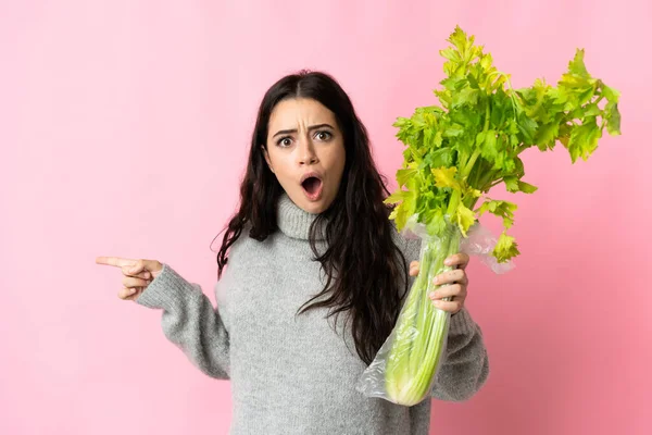 Young Caucasian Woman Holding Celery Isolated Blue Background Surprised Pointing — Foto de Stock