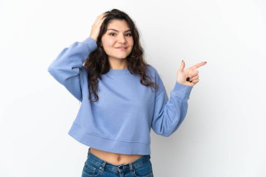 Beyaz arka planda izole edilmiş genç Rus kız şaşırmış ve parmağıyla kenarı işaret ediyor.