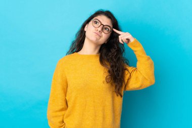 Teenager Russian girl isolated on blue background making the gesture of madness putting finger on the head