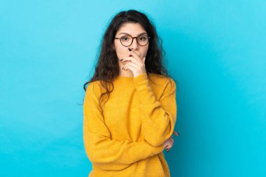 Teenager Russian girl isolated on blue background surprised and shocked while looking right