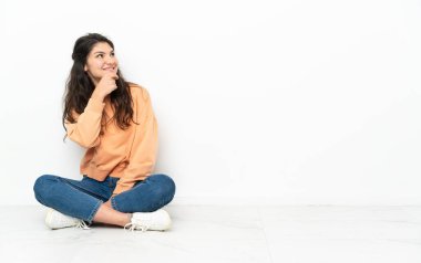 Genç Rus kız yerde oturuyor, yan tarafa bakıyor ve gülümsüyor.