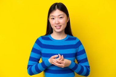 Sarı arka planda yalnız yaşayan genç bir Çinli kadın gülüyor.