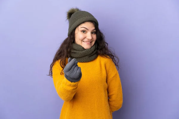 俄罗斯少女 头戴紫色背景的冬帽 做着赚钱的姿势 — 图库照片