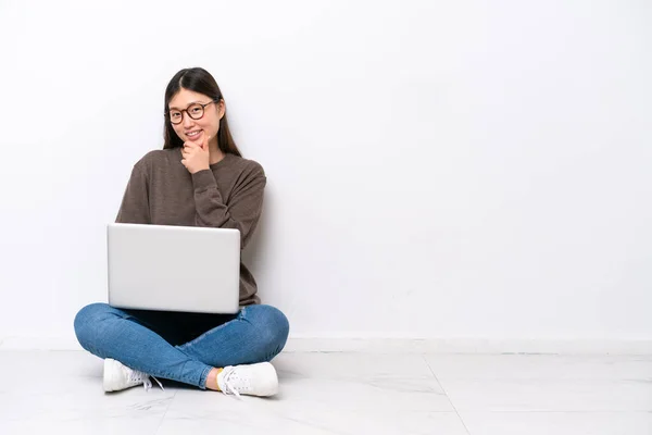 拿着笔记本电脑的年轻女人坐在地板上 戴着眼镜 面带微笑 — 图库照片