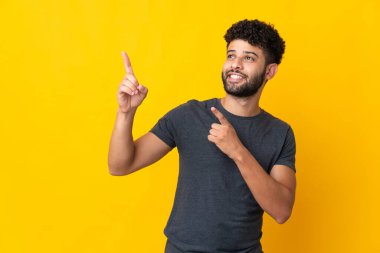 Faslı genç adam sarı arka planda izole edilmiş işaret parmağıyla işaret etmek harika bir fikir.