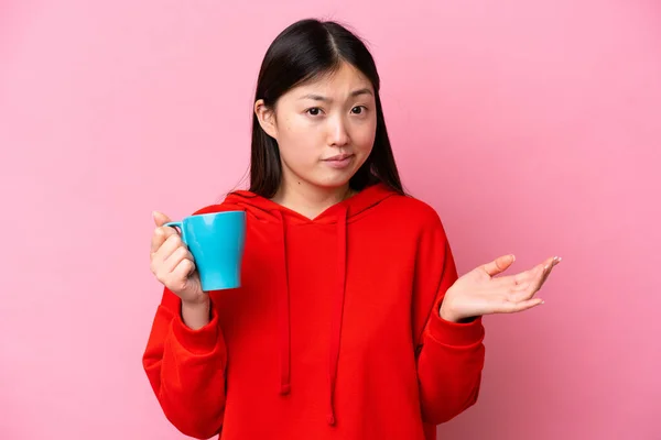 Молодая Китаянка Держит Чашку Кофе Изолированы Розовом Фоне Делает Сомнения — стоковое фото