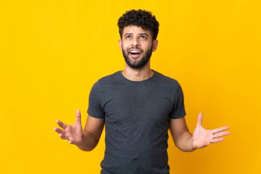 Sarı arka planda izole edilmiş genç Faslı bir adam stresli.